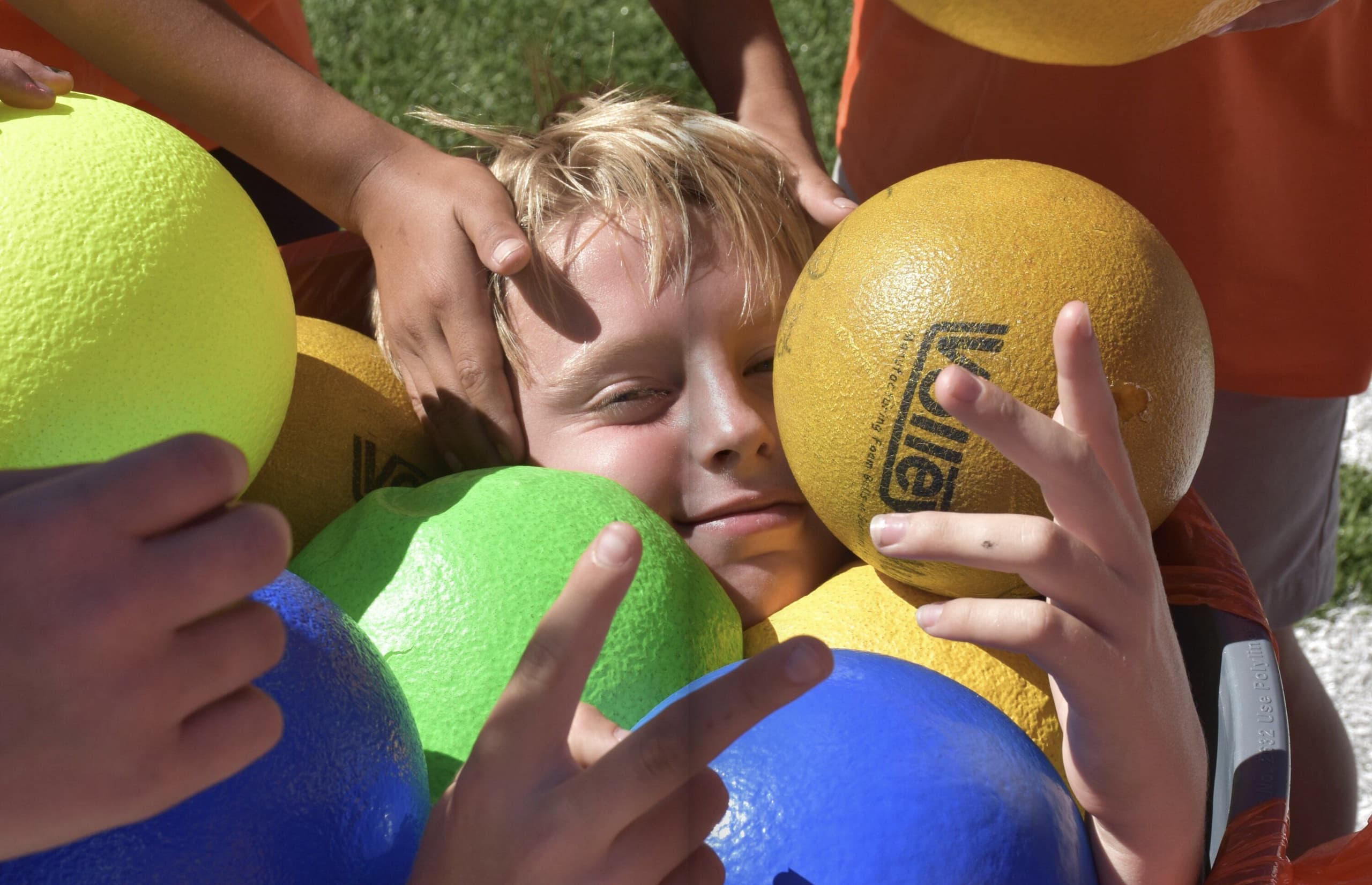 A student reaches into a bin of brightly colored playground balls during an activity.