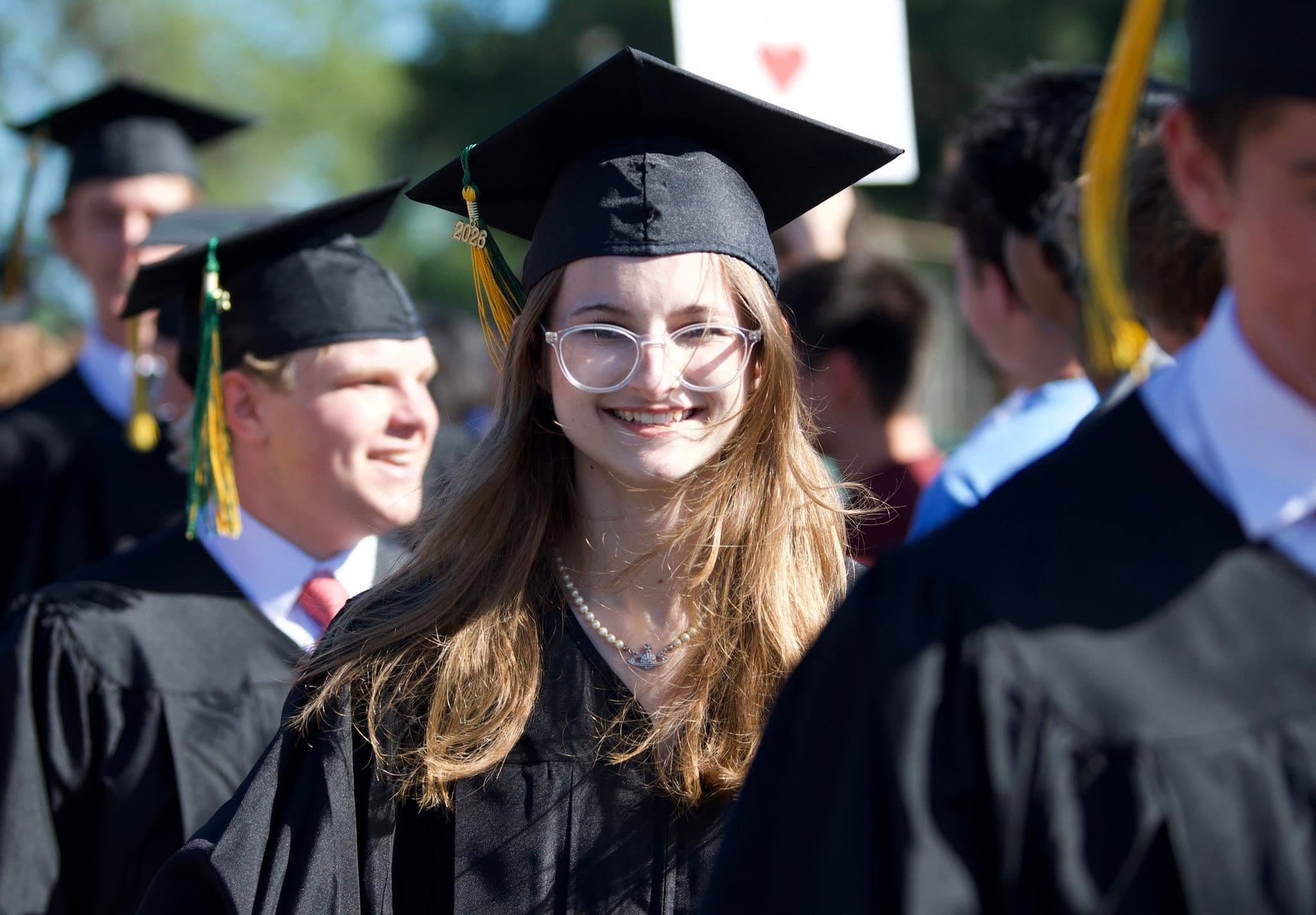 A graduate in cap and gown smiling in the 2026 processional