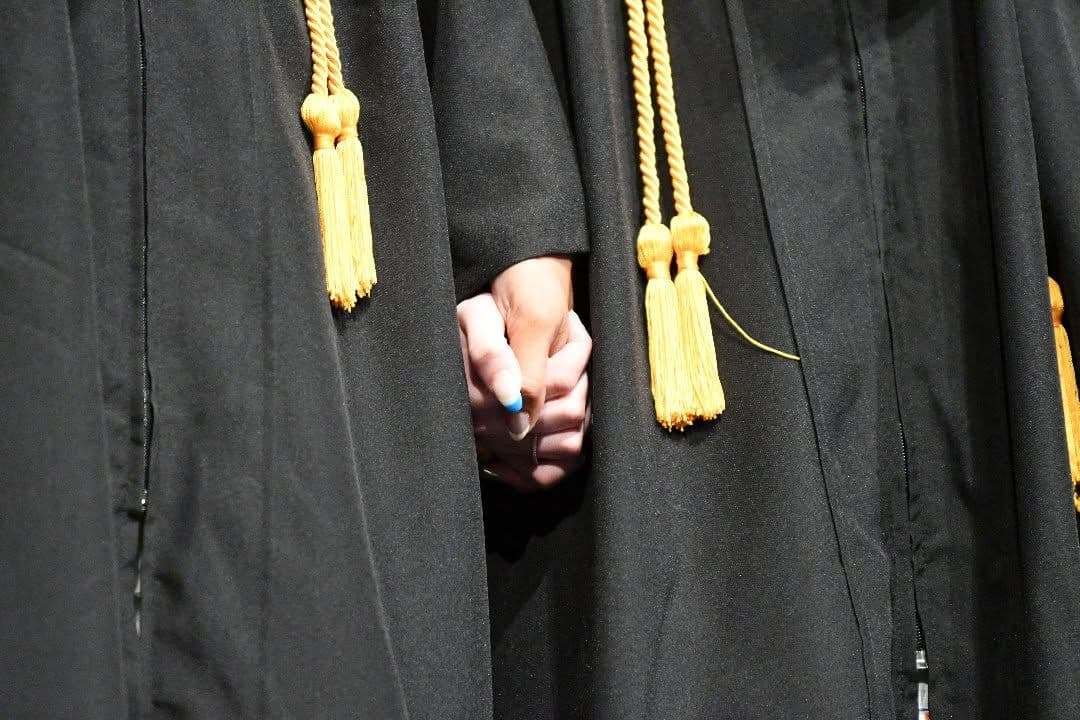 Students hold hands at graduation