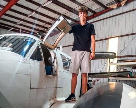 Student standing on airplane in hangar