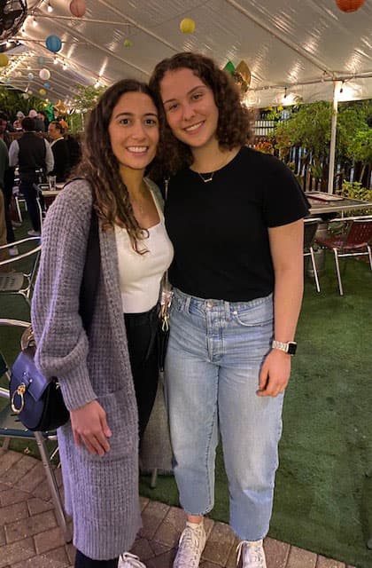 Two alumni under an outdoor tent