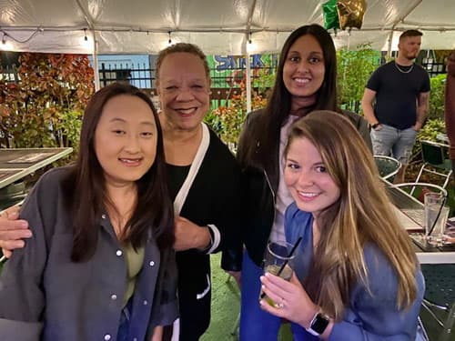 Eileen Price with several alumni under an outdoor tent