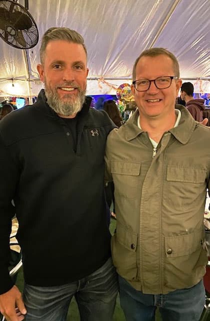 Two alumni under an outdoor tent