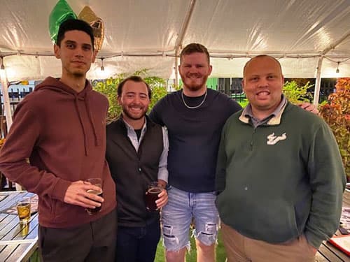 Four alumni under an outdoor tent